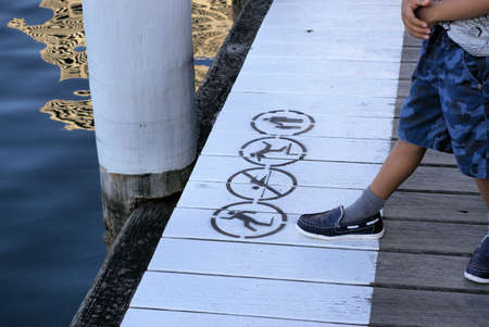 Warning signs near water. Kid steps on water danger signs warning people about falling into water, slipping into water, no swimming and parents to hold kid's hand.の写真素材