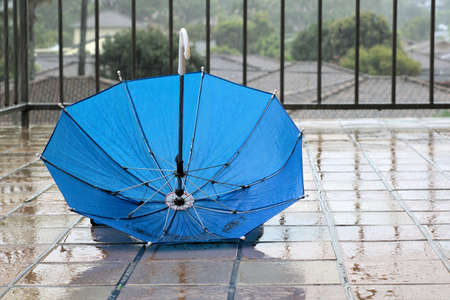 Umbrella in rain. Blue umbrella upside down in rain on wet floorの写真素材