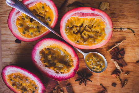 Close up yellow color passion fruit pulp and seed in small ceramic bowl isolated on BROWN board, spoon, spicesの写真素材