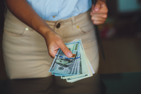 Money in human hands, women giving a lot of 100 dollars, with business folders , on a black の写真素材