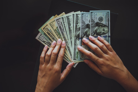 Money in human hands, women counting a lot of 100 dollars, with business folders , on a black の写真素材