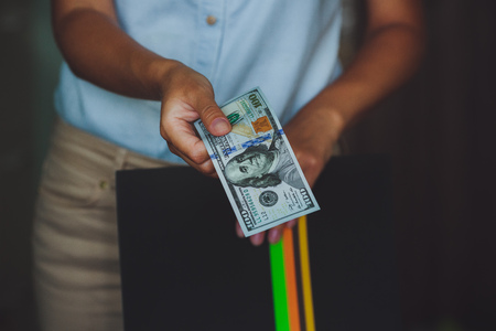 Money in human hands, women giving 100 dollars, with business folders , on a black backgroundの写真素材