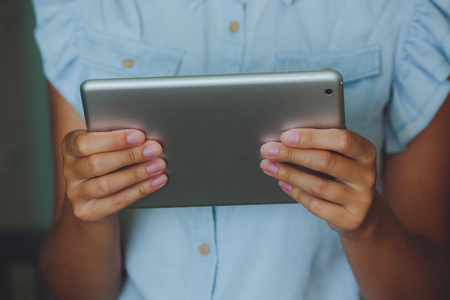 Businesswoman uses digital tablet. The tablet has a gray case and a glass screen. The woman in blue shirt.の写真素材