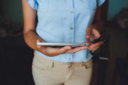Businesswoman uses digital tablet. The tablet has a gray case and a glass screen. The woman in blue shirt.の写真素材