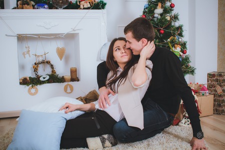 couple man and woman hugging, lie near the Christmas treeの写真素材