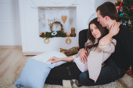 couple man and woman hugging, lie near the Christmas treeの写真素材