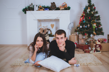 couple man and woman hugging, lie near the Christmas treeの写真素材