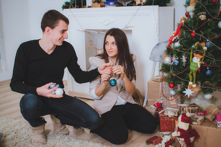 man and woman celebrating Christmas and decorating a Christmas tree with toysの写真素材