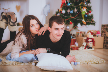 couple man and woman hugging, lie near the Christmas treeの写真素材