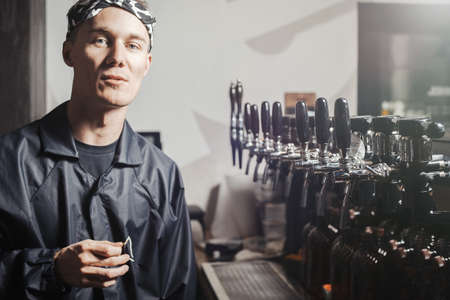 Bartender man stands next to beer faucets.の写真素材