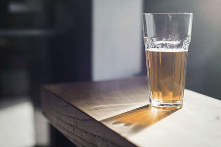Glass of beer on wooden table at bar.の写真素材