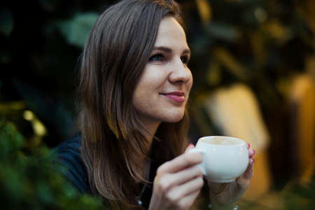 Young pensive attractive girl drinking coffee from white cup.の写真素材