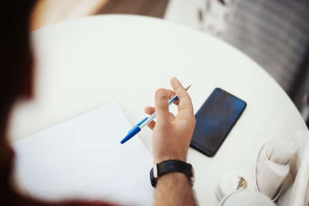 Young attractive man is writing note at the paper.の写真素材