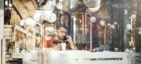 Young attractive man drinking coffee at lunch timeの写真素材