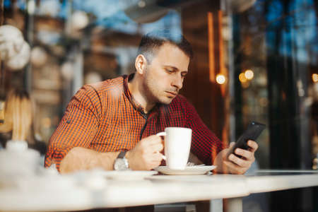 Young attractive man drinking coffee at lunch timeの写真素材