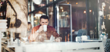 Young attractive man drinking coffee at lunch timeの写真素材
