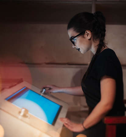 Young brunette girl student with glasses and black lipstick reading Ebook in the universityの写真素材