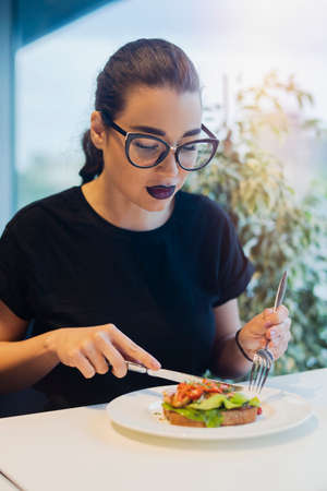Young attractive girl is eating bruschetta at business lunch. Girl is on focus, food is blurred.の写真素材