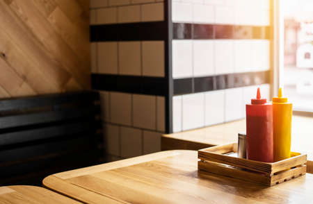 Ketchup and mustard bottles are on table close up.
