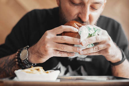 Young bearded man eating burger.の写真素材
