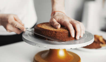 Close up of cook cutting cake on a cake stand.