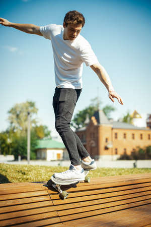 Young attractive man in white T-shirt riding longboard in the park.の写真素材
