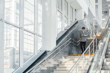 Distant plan of young attractive man going down the stairs in metro station.の写真素材