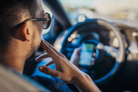 Close up of young man looking at GPS navigator behind the wheel in car. Man is on focus and...