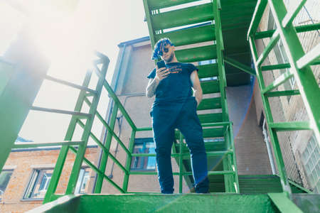 Young man with blue dreadlocks dancing reggaeton on green stairs. Man is on focus and foreground, green stairs is on background and blurred.の写真素材