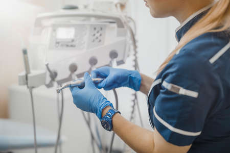 Close up of woman dentist in blue uniform checking dental equipment.