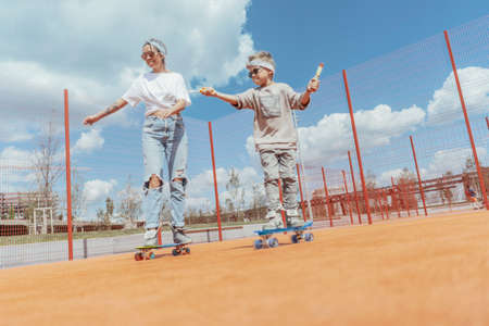 Close up of skateboarding family at playground. Happy family concept. Family is on focus and foreground, playground is blurred.の写真素材