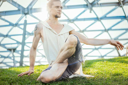 Close up of attractive athletic man practicing yoga and warming up outdoors.の写真素材