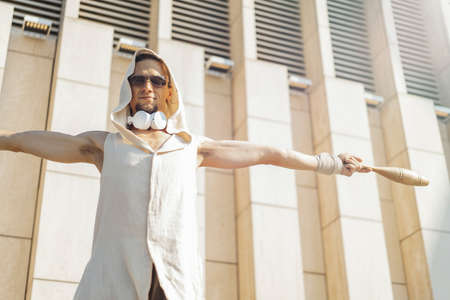 Attractive athletic man practicing yoga with maces outdoors in modern park.の写真素材