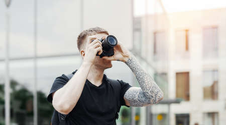 Attractive man making photos outdoors at cityscape backgroundの写真素材