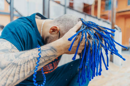 Young attractive man with blue dreadlocks touching his hair.の写真素材