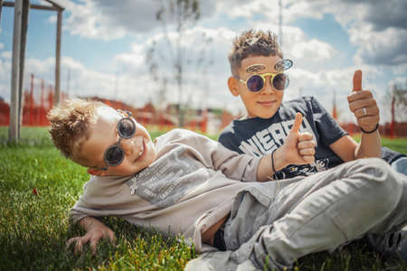 Close up of boys sitting in the park on green grass. Happy family concept.の写真素材
