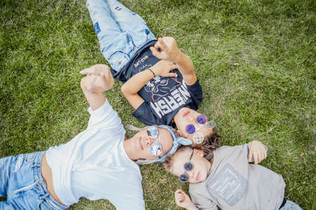 Close up of mum and sons lying in the park on green grass. View from above. Happy family concept.の写真素材