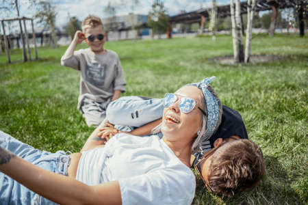 Close up of mum and sons lying in the park on green grass. Side view. Happy family concept.の写真素材