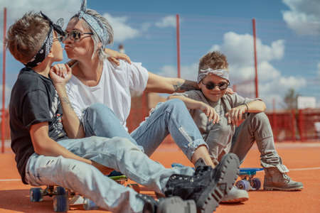 Young mum sitting with her sons at playground. Happy family concept.