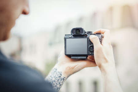 Close up of man hands holding camera and making photos of modern building.の写真素材