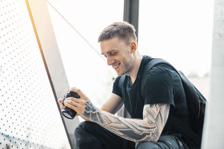 Attractive man sitting at staircase, smiling and checking photos in camera.の写真素材