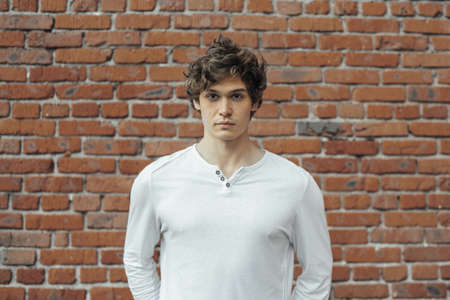 Close up of young attractive man standing on red brick background.