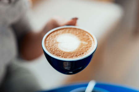 Close up of woman hands holding blue cup of coffee.