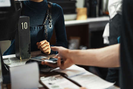 Customer paying via modern payment terminal using mobile phone. NFC payment.