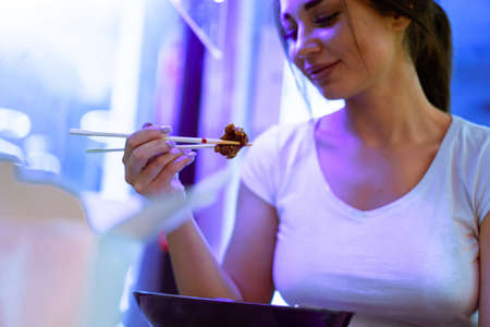 Close up of attractive woman eating asian food with chopsticks at restaurant.の写真素材