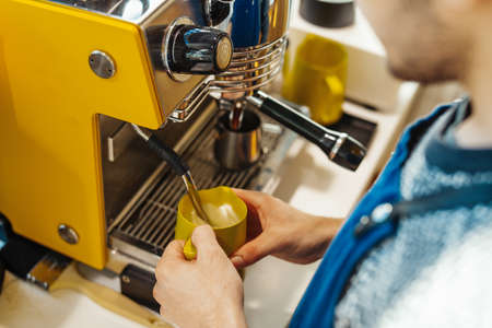 Close up of barista steaming milk in the pitcher with coffee machine preparing to make latte art in cafe. Barista preparing cappuccino with coffee machine. Coffee Preparation Service Concept.の写真素材