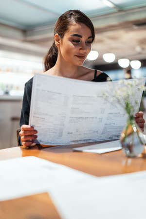 Young beautiful woman looking at menu deciding what to order in modern cafe at date.の写真素材