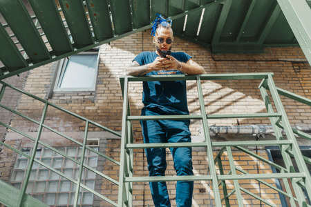 Young attractive man with blue dreadlocks standing at staircase.