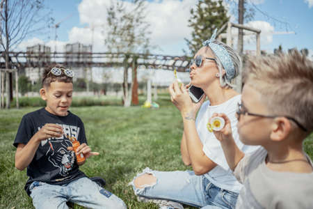 Happy family blowing bubbles outdoors in the park and having fun.の写真素材