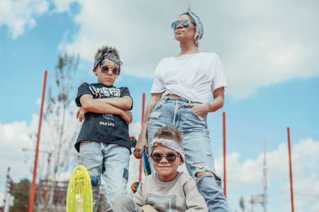 Young woman standing with her sons at playground. Happy family concept.の写真素材